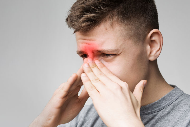 Man holding nose in pain