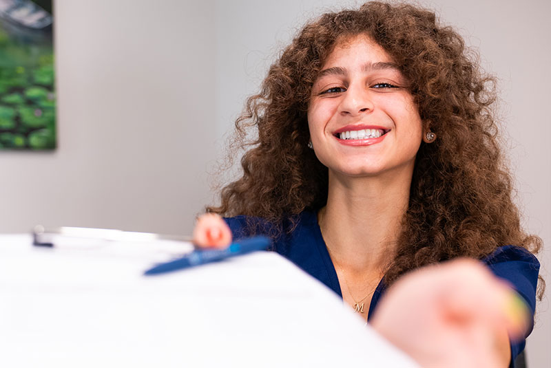 Team member handing insurance papers to Patient
